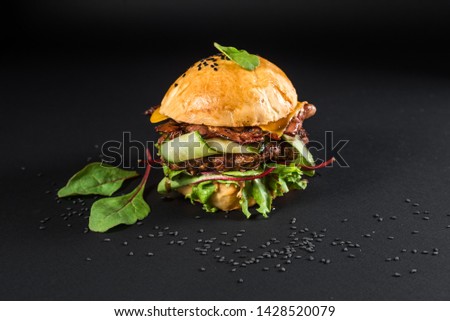 Tasty craft burger with grilled meat, cheese, tomato on the black background