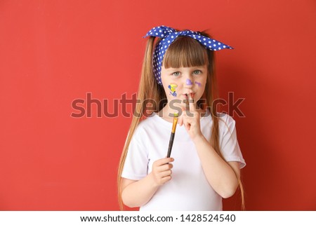 Cute little artist showing silence gesture on color background
