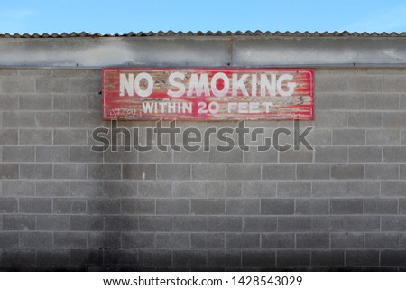 Weathered "No Smoking" sign on cinderblock building