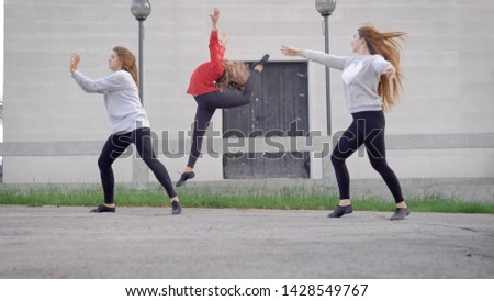 three pretty young modern ballerinas is dancing contemporary dances on a street, performing different movements