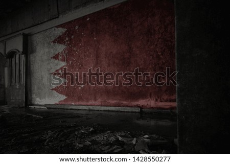 painted flag of bahrain on the dirty old wall in an abandoned ruined house. concept