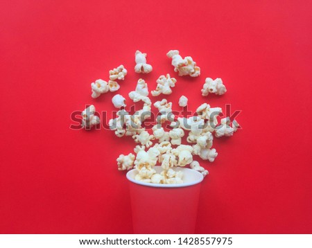 Popcorn in a paper cup On a red background. movies and entertainment concept