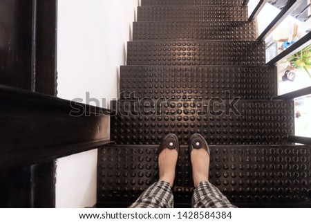 Young women's feet in front of the black steel stairs down.
