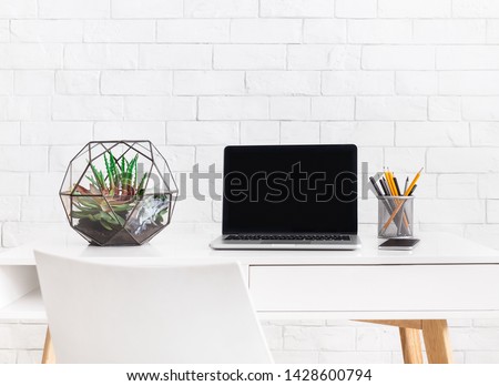Modern home working place with laptop, and florarium vase with home plants at white brick wall background. Scandinavian style concept