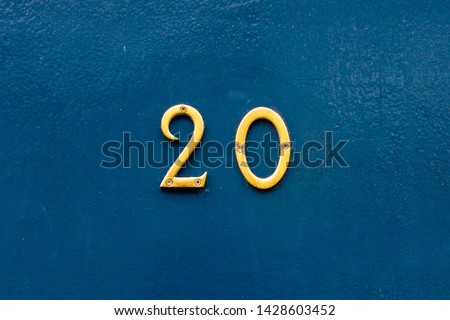 House number 20 in thin bronze metal numbers - the twenty is on a blue wooden front door Royalty-Free Stock Photo #1428603452