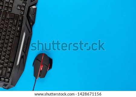 An amazing keyboard and an awesome mouse on blue background, shot from above.