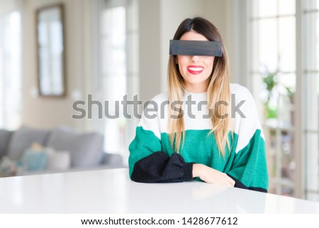 Young beautiful woman blindfold eyes with black censor band at home with a happy and cool smile on face. Lucky person.