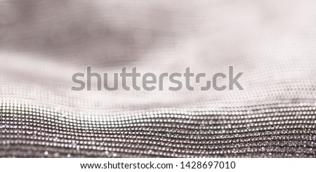 Background texture of shiny fabric with bokeh light. Beautiful festive christmas background for greeting design. Nacreous sparkling white texture.