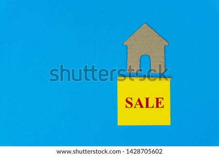 Home for sale. Property sale concept. Real estate sale sign under a small house made by paper cut on blue background.