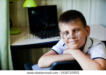 technology, games and people concept - portrait of a boy in his room on the background of a laptop look at us