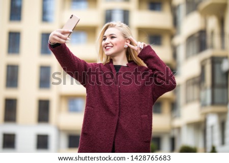 Young girl take selfie from hands with phone on summer city street. Urban life concept.