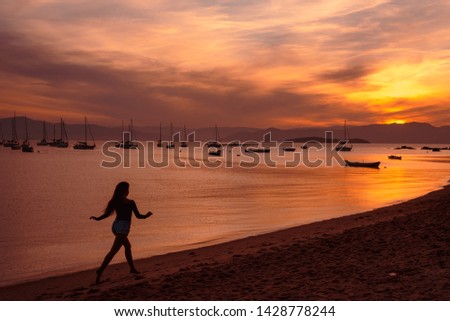 The silhouette of a girl running in the beach at the sunset in Santo Antonio de Lisboa, Florianopolis, Santa Catarina, Brazil