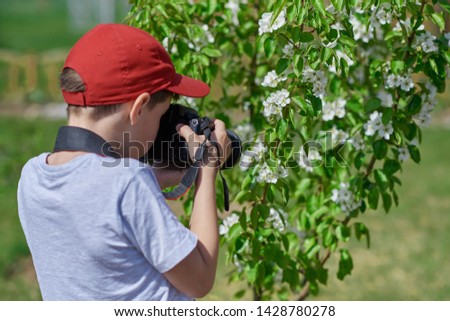 Boy using digital camera taking photo in the nature, hobbies concept Image.