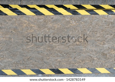 Chipboard wall background with yellow and black police tape, texture.