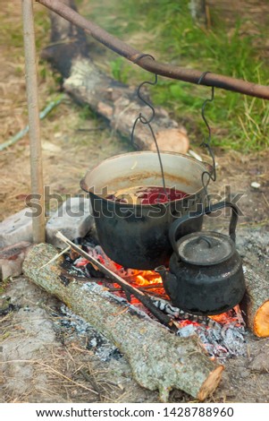 Two smoked tourist kettles over camp fire. Process of cooking on the nature.