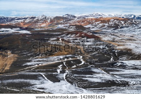 Panorama view of the volcanic landscape with snowcapped mountains of Myvatn, northern Iceland from the Hverfjall volcano crater. Top left of picture is the Myvatn nature thermal bath facility.