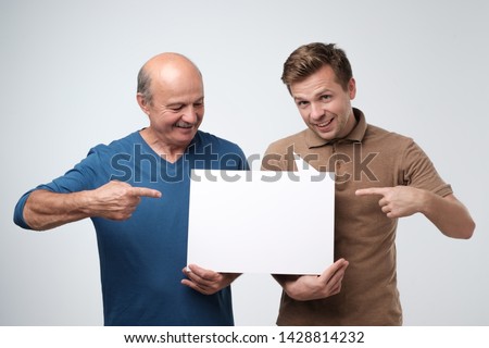 two mature men showing empty copyspace for ad. Family small business concept