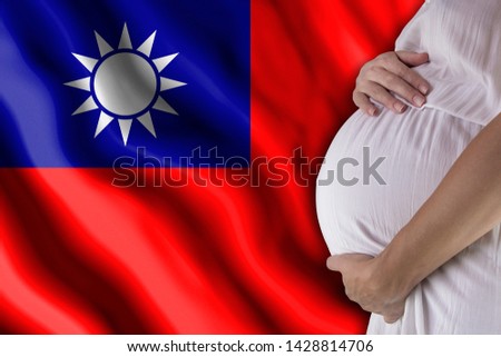 Conditions of birth of the child, the childbirth allowance, state support for young mothers, a pregnant girl holds her hands on the stomach close-up against the background of the flag of Taiwan