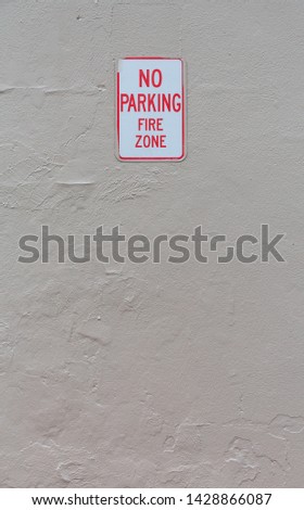 Concrete painted wall with a no parking fire zone sign.