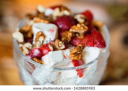 Vanilla ice cream with strawberry and walnut in bowl on blurred background