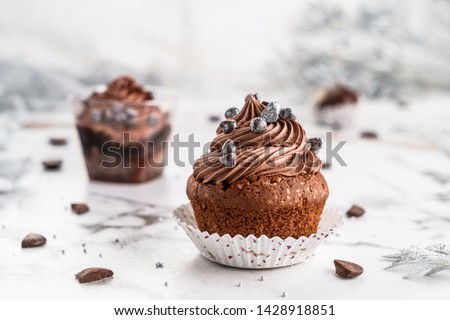 Cupcakes or muffins with chocolate cream and candy on light marble background. Holiday cake celebration, delicious dessert, close up Royalty-Free Stock Photo #1428918851