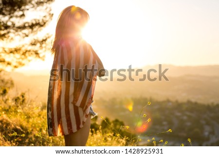 Beautiful woman wearing the American flag looking out at sunset looking content