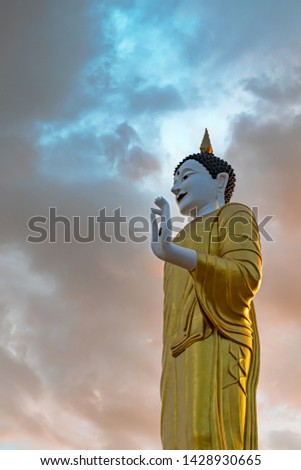 The attitude of blessing, standing buddha image, coloured as northern thailand style with colorful gradation cloud and sunlight