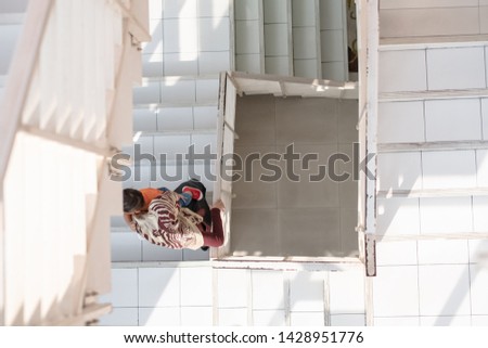 Top view of Thai muslim mother carrying baby boy walking down the stairs. Love and care of mother concept.