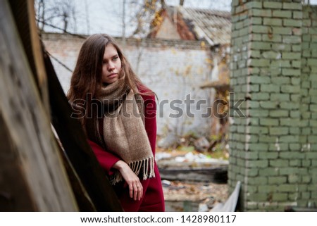 Girl with long hair in a red coat in an abandoned old building in late autumn