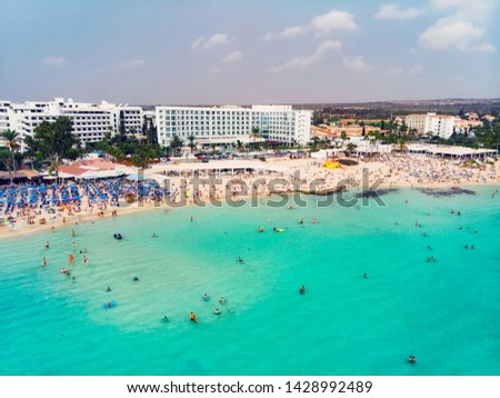 Colorful picture of the beach of Ayia Napa with some of the resorts and straw sunshade umbrellas