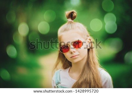 A close up portrait of a beautiful teenager girl posing in the field. Kids, nature, summer casual fashion, beauty.