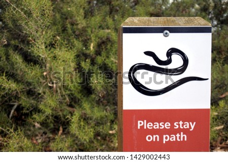A snake icon with please stay on path text on outdoor sign in Australian park.