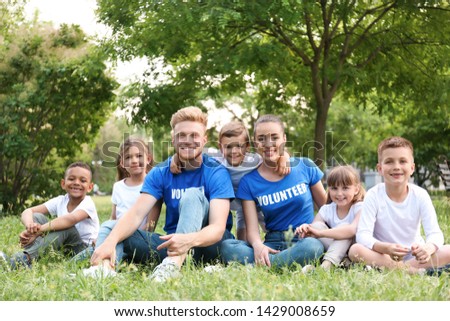 Volunteers and kids sitting on grass in park