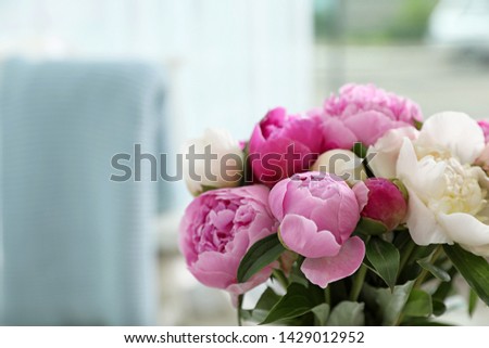 Bouquet of beautiful peonies in room, space for text