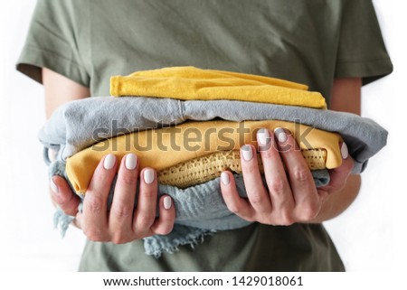 Stack of clothes in woman’s hands on white background isolation