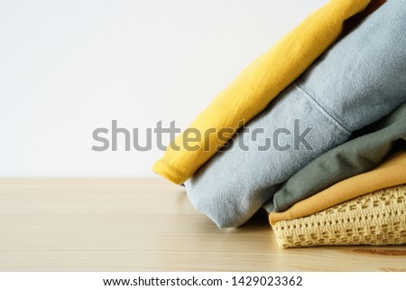 Stack of clothes on wooden table and white background