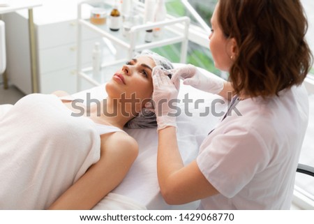 Female beauty. Top view of a beautiful nice woman lying on the medical bed while receiving injections