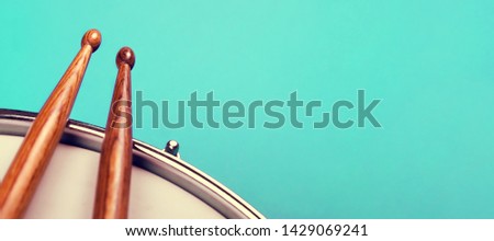 Fragment of a Snare drum and drumsticks on light blue background with copy space for text. Music festival and study and school advertising concept. Banner format.