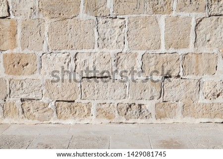 Rough yellow stone wall and gray floor tiling, empty Interior background texture
