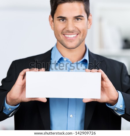 Portrait of businessman holding blank placard in office