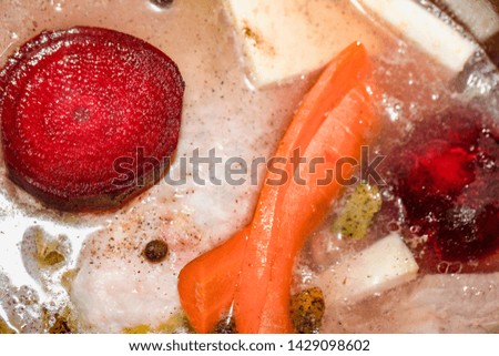 Cooking broth (soup stock) in a pot, Closeup photo. Celery, carrots, beetroots and meat in a boiling water.