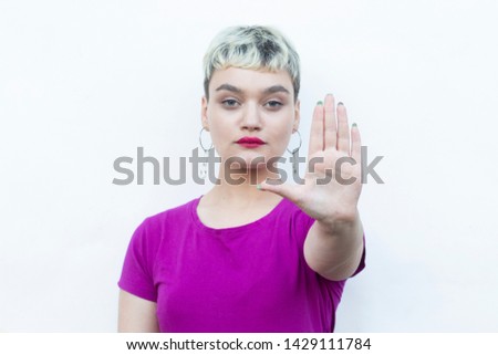 Young blond woman doing ok sign with fingers, showing hush sign with serious expression,showing stop gesture, excellent symbol, isolated over white background
