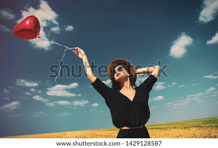 photo of the beautiful young woman with heart-shaped balloon in the field