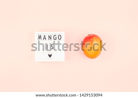 Mango fruit in creative conceptual top view flat lay composition with lightbox with Mango is love slogan isolated on pink background in minimal style with copy space. Pop art concept poster