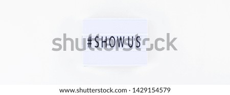 Creative top view flat lay of lightbox with hashtag Show Us message white background minimal style. Concept of Project world largest stock photo collection created by women