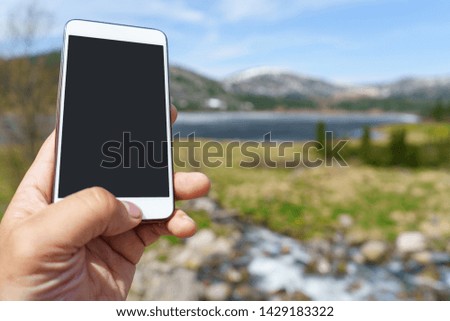 The hiker uses a smart phone in the mountains