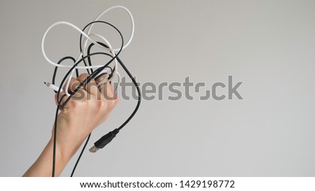 Black and white cables in a left woman's hand on a light gray background Royalty-Free Stock Photo #1429198772