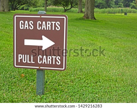 An Arrow Pointing Towards the Gas Carts Pull Carts Golf Course Sign Positioned near A Cart Path 