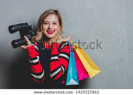 Young woman with binoculars and shopping bags