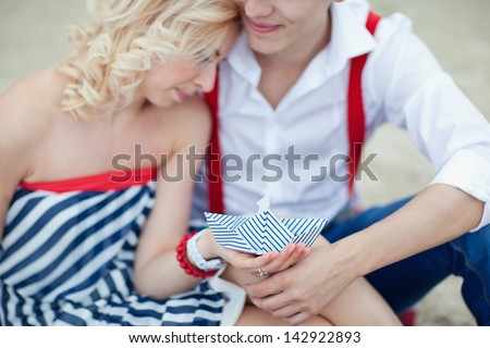 Honeymoon. Young beautiful man and woman couple sailors are holding a paper boat.